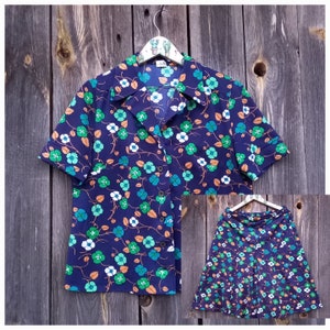 May include: A blue and white floral print blouse and skirt set. The blouse has a collared neckline and short sleeves. The skirt is a-line and has a high waist.