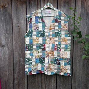 Op de afbeelding: Een sleeveless vest met een geruit patroon in tinten blauw, groen, wit en bruin. Het vest heeft een knoopsluiting en een klein label met de tekst "Miss Joy".