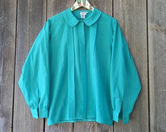 May include: A teal blue blouse with a peter pan collar and long sleeves. The blouse has a button-up front and is pleated down the front.