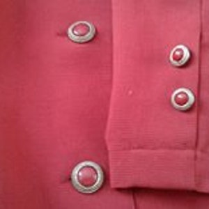 May include: Red blazer with four silver buttons with red stones. The buttons are on the front and sleeves of the blazer.