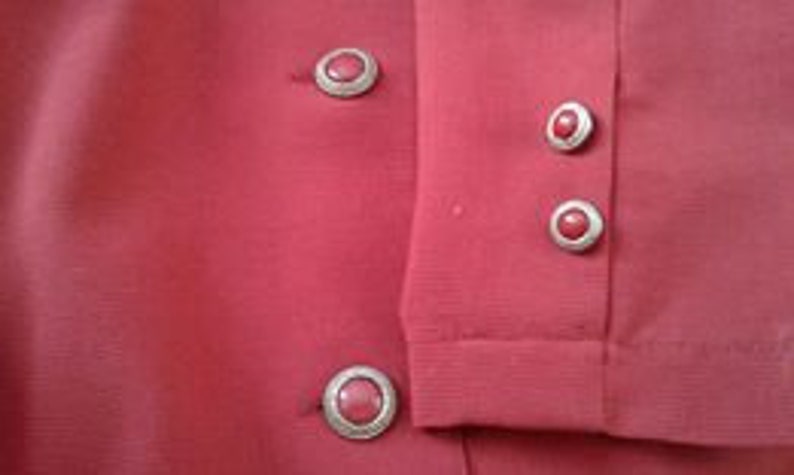 May include: Red blazer with four silver buttons with red stones. The buttons are on the front and sleeves of the blazer.