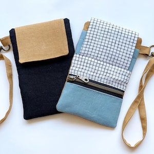 May include: Two small fabric crossbody bags. One is black with a tan flap, the other is blue and white checkered with a blue bottom and a zipper. Both have tan straps and metal hardware.