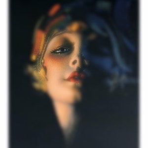 Pu&ograve; includere: Un ritratto ravvicinato di una donna con capelli scuri e labbra rosse. Indossa un foulard colorato sulla testa e i suoi occhi guardano direttamente la fotocamera.
