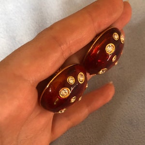 May include: A pair of red and gold tone clip-on earrings with clear rhinestones.