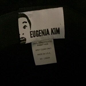 May include: White tag with black text that reads "EUGENIA KIM", "100% DOMESTICATED RABBIT HAIR", "SPOT CLEAN ONLY", "MADE IN U.S.A.", and "RN 126634".