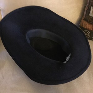 May include: A black felt fedora hat with a wide brim. The hat is turned inside out, showing the dark gray lining.