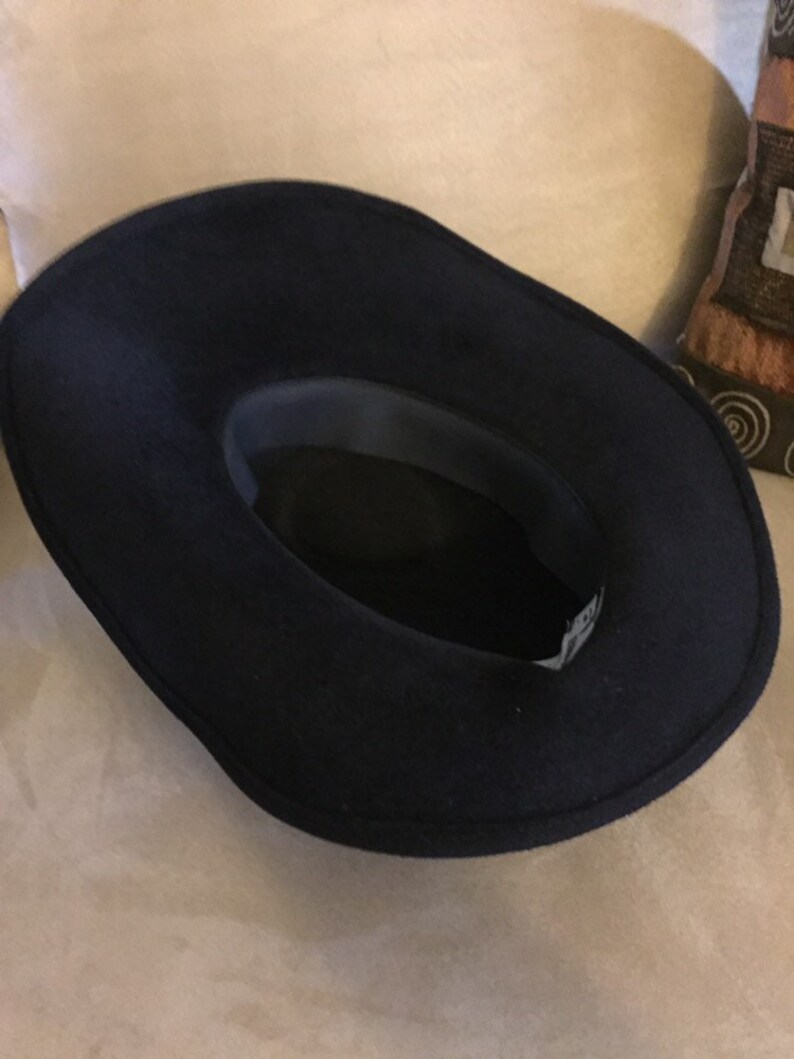 May include: A black felt fedora hat with a wide brim. The hat is turned inside out, showing the dark gray lining.