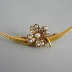 May include: A gold crescent moon brooch with a four-leaf clover design set with pearls.
