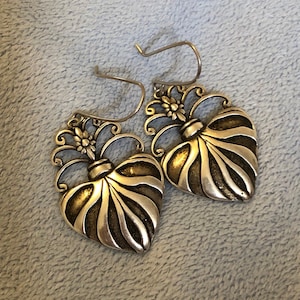 May include: A pair of silver heart-shaped earrings with intricate floral details. The hearts have a textured, ribbed design.