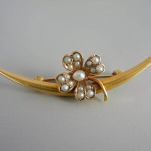May include: A gold crescent moon brooch with a four-leaf clover design set with pearls.