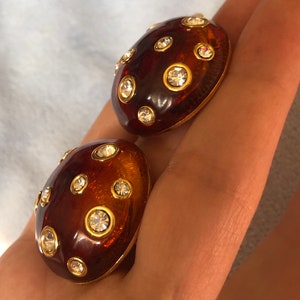 May include: A pair of brown and gold tone clip-on earrings with clear rhinestones.