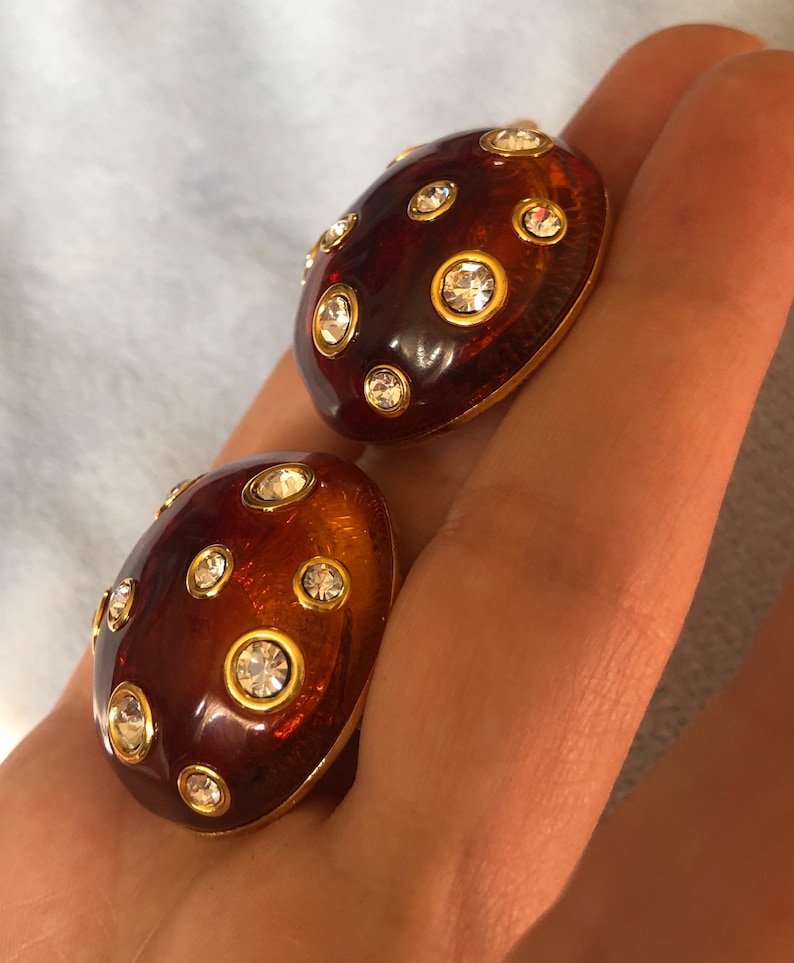 May include: A pair of brown and gold tone clip-on earrings with clear rhinestones.