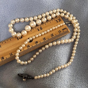 May include: A white pearl necklace with a silver clasp. The necklace is approximately 12 inches long and is made of small, round pearls.