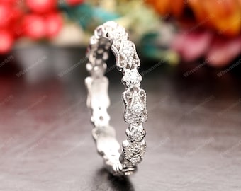 May include: A delicate silver band with a row of small, sparkling diamonds set in a delicate floral design.