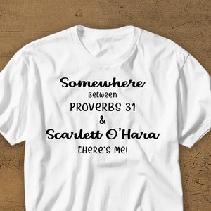 Puede incluir: Camiseta blanca con texto negro que dice "Somewhere between Proverbs 31 & Scarlett O'Hara there's me!"