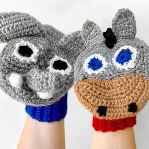 Könnte beinhalten: Zwei handgefertigte Häkeltierpuppen: ein graues Kaninchen mit blauen Manschetten und ein grauer Esel mit brauner Schnauze und roten Manschetten. Die Puppen haben schwarze und weiße Details für Augen und Mund.