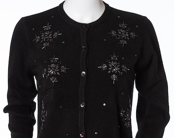 May include: A black cardigan sweater with a button-up front and long sleeves. The sweater is decorated with embroidered snowflake designs and sequins.