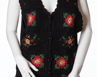 May include: A black crocheted vest with a floral design. The vest has a V-neck and is adorned with red, green, and gold embroidery.