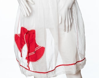 May include: White apron with a red heart-shaped pocket. The apron has a red trim around the bottom edge.