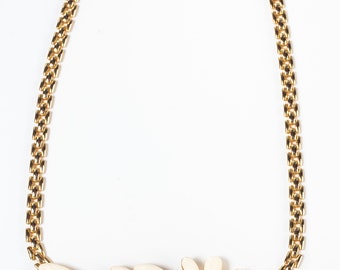 Può includere: Una collana a catena dorata con un ciondolo a forma di fiore in smalto bianco e blu.