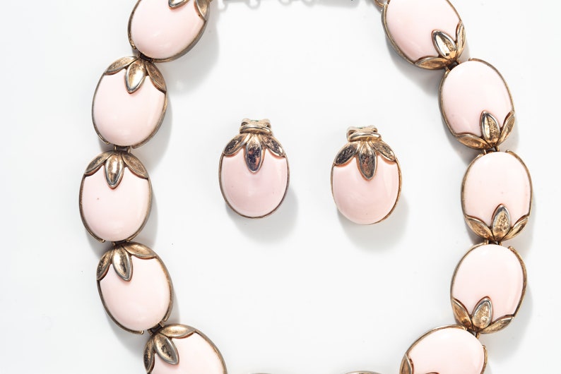 Puede incluir: Un conjunto de collar y pendientes de color rosa y dorado. El collar est&aacute; hecho de piedras rosas ovaladas con detalles dorados. Los pendientes tambi&eacute;n son ovalados y tienen un dise&ntilde;o similar.