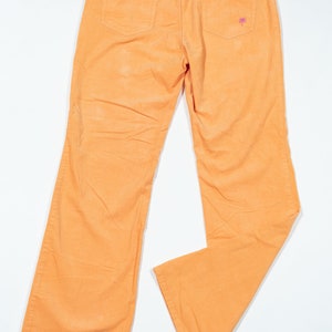 May include: A pair of orange corduroy pants with a small pink palm tree embroidered on the back pocket.
