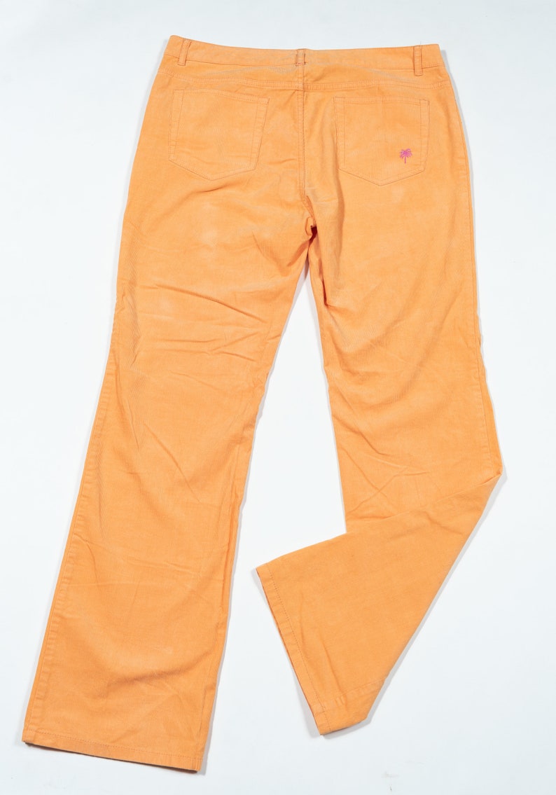 May include: A pair of orange corduroy pants with a small pink palm tree embroidered on the back pocket.