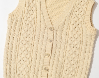 May include: A cream-colored cable knit sleeveless sweater vest with a V-neck and button closure. The label reads "The China Closet".