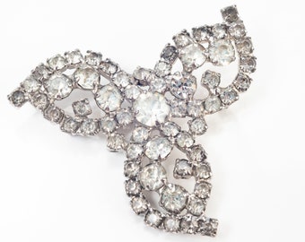 Può includere: Un fermaglio d'argento con un design a tre foglie, ogni foglia è decorata con strass trasparenti.