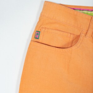 May include: Orange corduroy pants with a small pink and green patch on the front pocket.