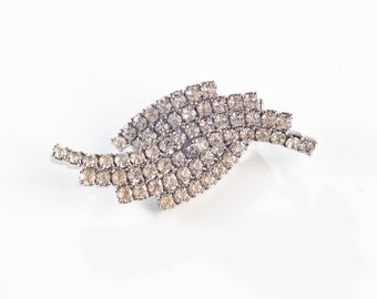 Può includere: Un fermaglio d'argento con un design a spirale fatto di strass trasparenti.