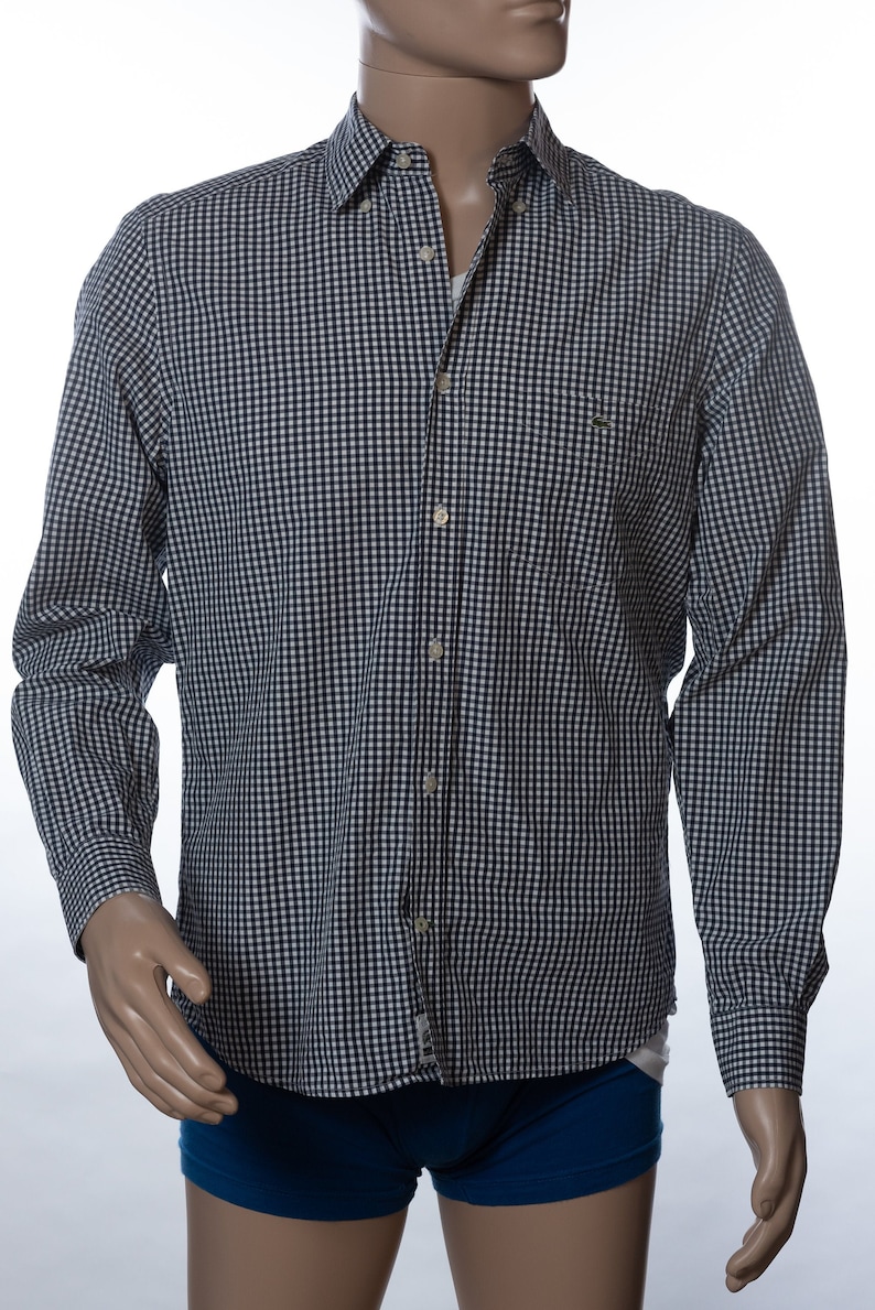 May include: A long-sleeved button-down shirt with a navy and white checkered pattern. The shirt has a classic collar, a chest pocket, and buttoned cuffs. The mannequin is also wearing blue underwear.