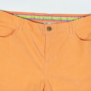May include: A pair of orange corduroy pants with a green and pink striped waistband.