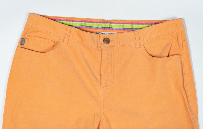 May include: A pair of orange corduroy pants with a green and pink striped waistband.
