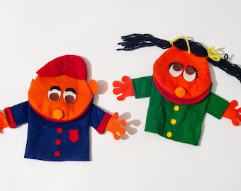 May include: Two felt hand puppets, one with a red hat and blue jacket, the other with a green jacket and black yarn hair.