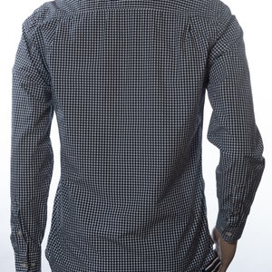 May include: A long-sleeved button-down shirt in a navy and white gingham pattern. The shirt is displayed on a mannequin, showcasing the back view. The cuffs have button closures. The shirt is made of a lightweight fabric.