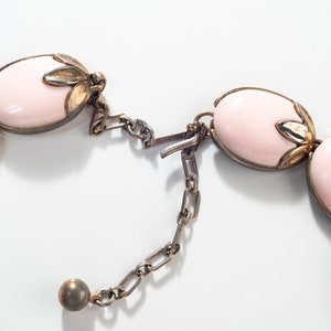 Puede incluir: Un collar rosa y dorado con piedras de forma ovalada y un cierre de cadena.