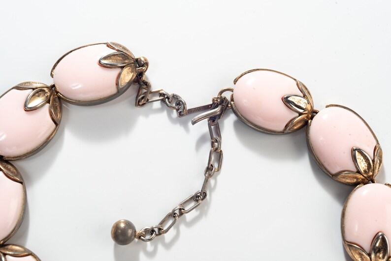 Puede incluir: Un collar rosa y dorado con piedras de forma ovalada y un cierre de cadena.