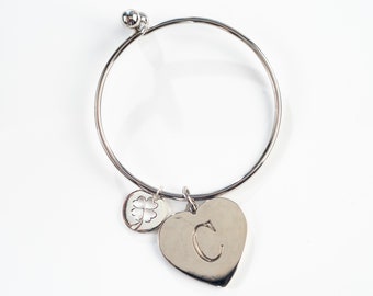 Può includere: Braccialetto rigido in argento con un ciondolo a forma di cuore inciso con la lettera C e un ciondolo a quattro foglie di trifoglio.