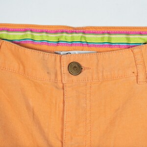 May include: A pair of orange corduroy pants with a striped waistband and a small palm tree button.