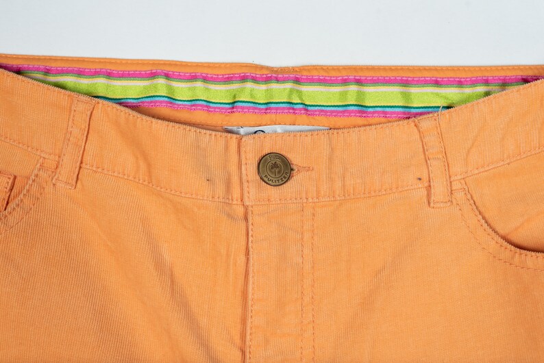 May include: A pair of orange corduroy pants with a striped waistband and a small palm tree button.