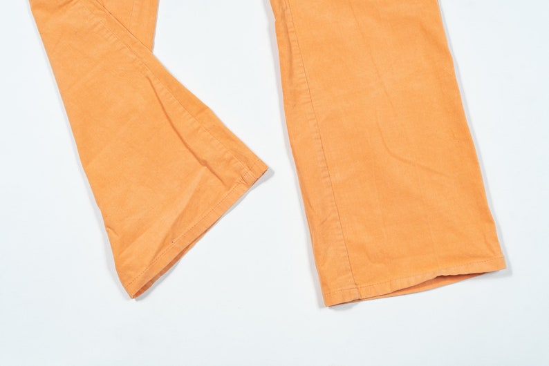 May include: A pair of wide-leg pants in a light orange color. The pants are made of a soft, textured fabric.