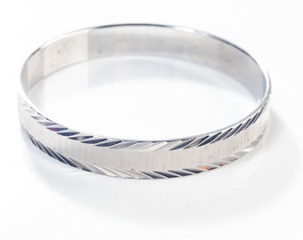 Può includere: Un braccialetto rigido in argento con un motivo testurizzato a forma di diamante.