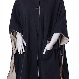 May include: A navy blue fleece poncho with a cream trim and two pockets. The poncho has a stand-up collar and buttons down the front.