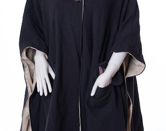 Puede incluir: Un poncho de forro polar azul marino con ribete crema y dos bolsillos. El poncho tiene un cuello alto y se abrocha con botones en la parte delantera.