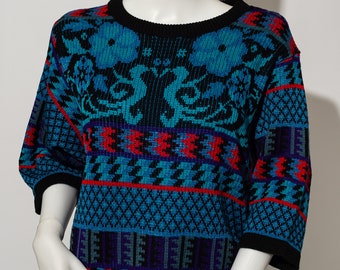 Può includere: Un maglione blu, nero, rosso e viola con motivo e collo rotondo nero.