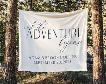 May include: A cream-colored banner with the words "and the ADVENTURE begins" in elegant script. Below, it reads "ADAM & BROOK COLLINS SEPTEMBER 20, 2025". The banner is suspended between two trees.