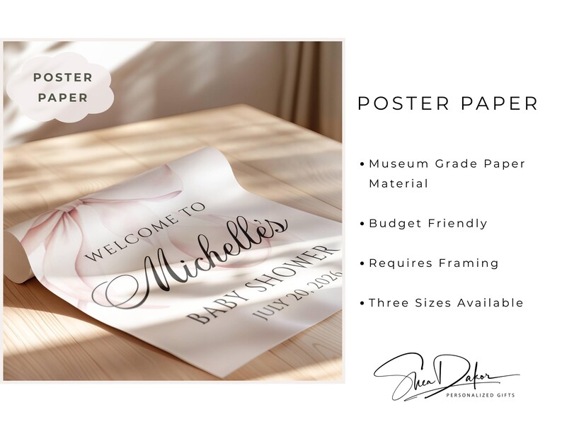 May include: A rolled poster on a wooden surface, featuring the text "Welcome to Michelle's Baby Shower July 20, 2026." The poster has a soft pink floral design. The words "Poster Paper" are in a cloud-shaped text box.