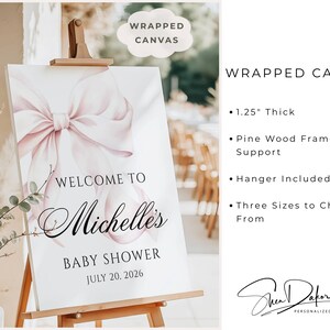 May include: A wrapped canvas baby shower sign on an easel. The sign features a large pink bow and the words "Welcome to Michelle's Baby Shower July 20, 2026." The sign is 1.25 inches thick and has a pine wood frame.