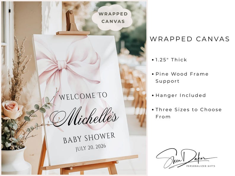 May include: A wrapped canvas baby shower sign on an easel. The sign features a large pink bow and the words "Welcome to Michelle's Baby Shower July 20, 2026." The sign is 1.25 inches thick and has a pine wood frame.